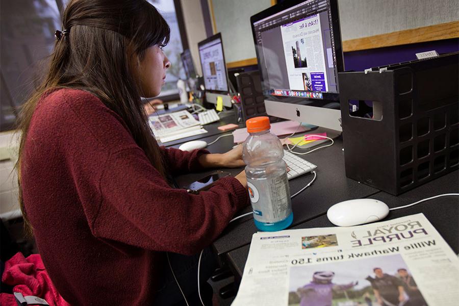 Student works on a computer for The Royal Purple.