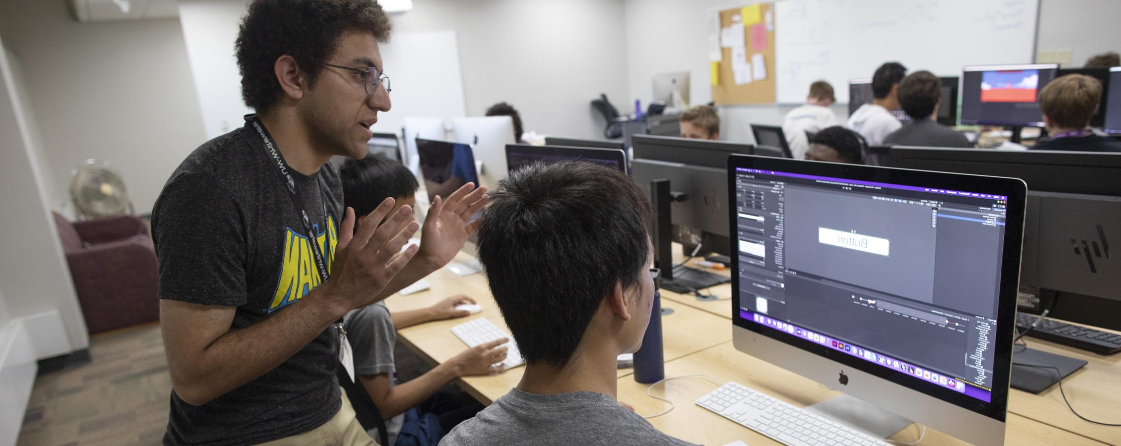 Students gather around computers to view their work.