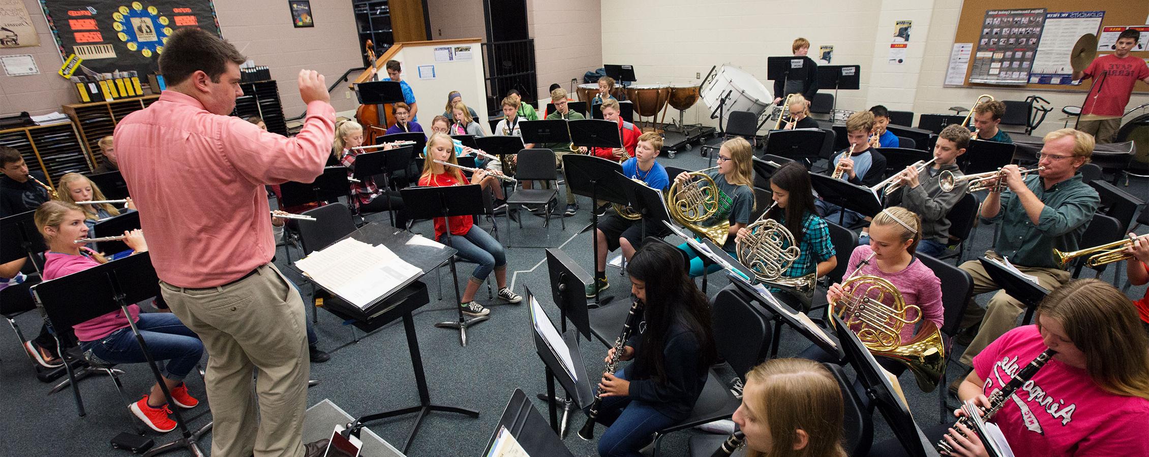 Elementary/Middle School music teacher conducting a group of students in rehearsal