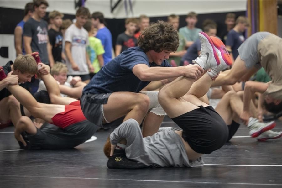 Students wrestling in a gym on a mat