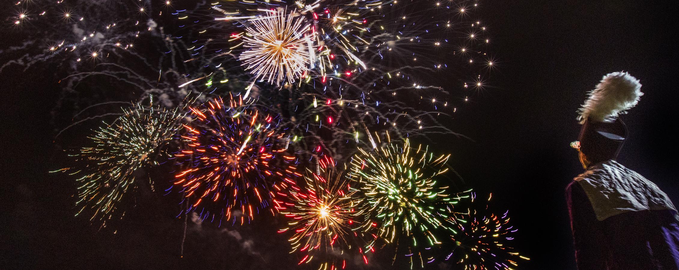 A Marching Band member watches fireworks.