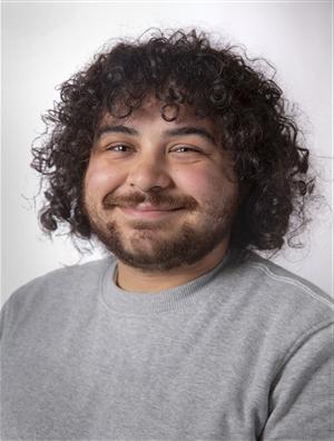 pacific islander man in early twenties with curly dark hair and dark eyes smiling