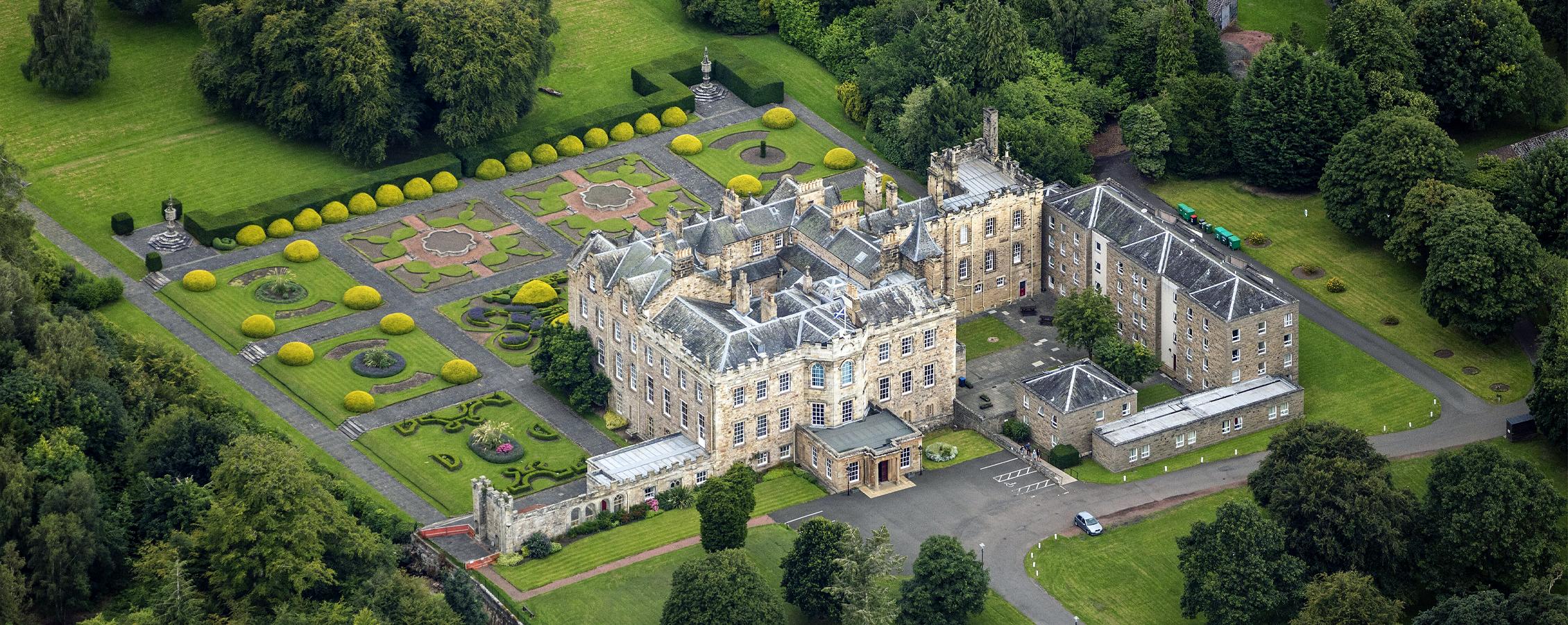 A photo of Dalkeith Palace, a sprawling three story castle with a stone exterior.