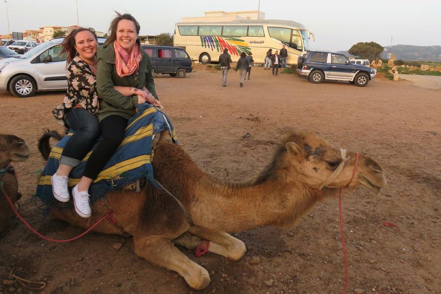 Two people sit on a camel.