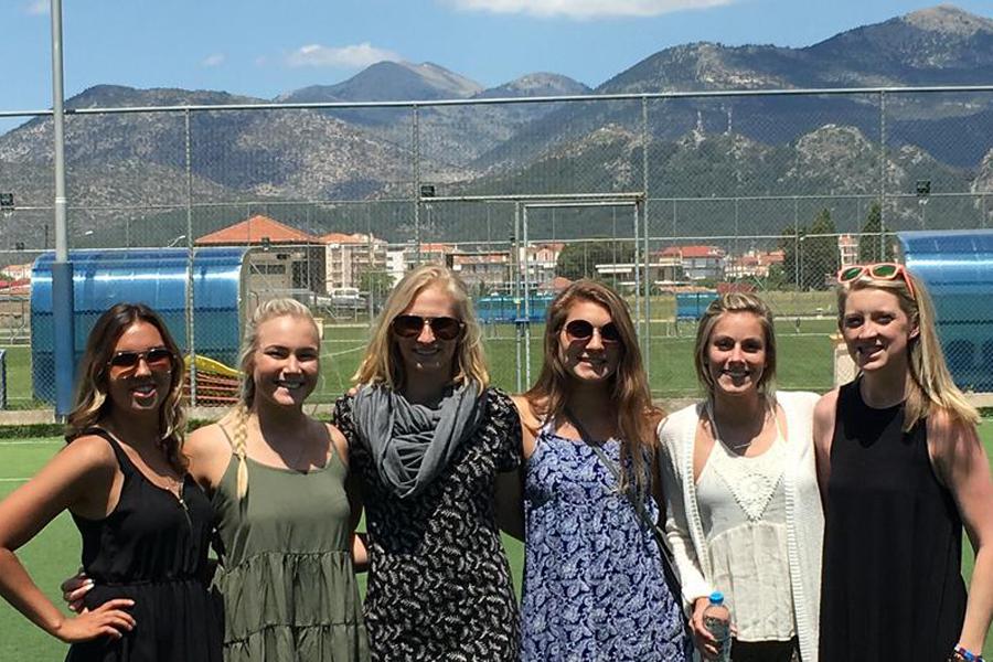 Student athletes stand together and smile at the camera with mountains in the background.