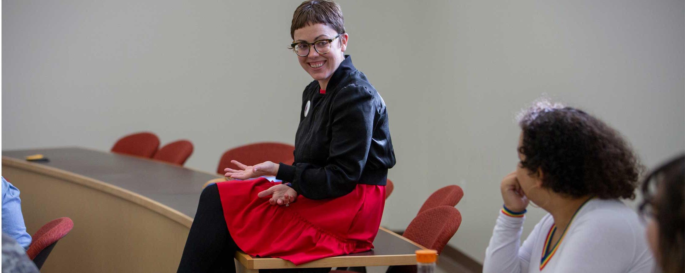 Stephanie Selvick sits on a table talking with students.