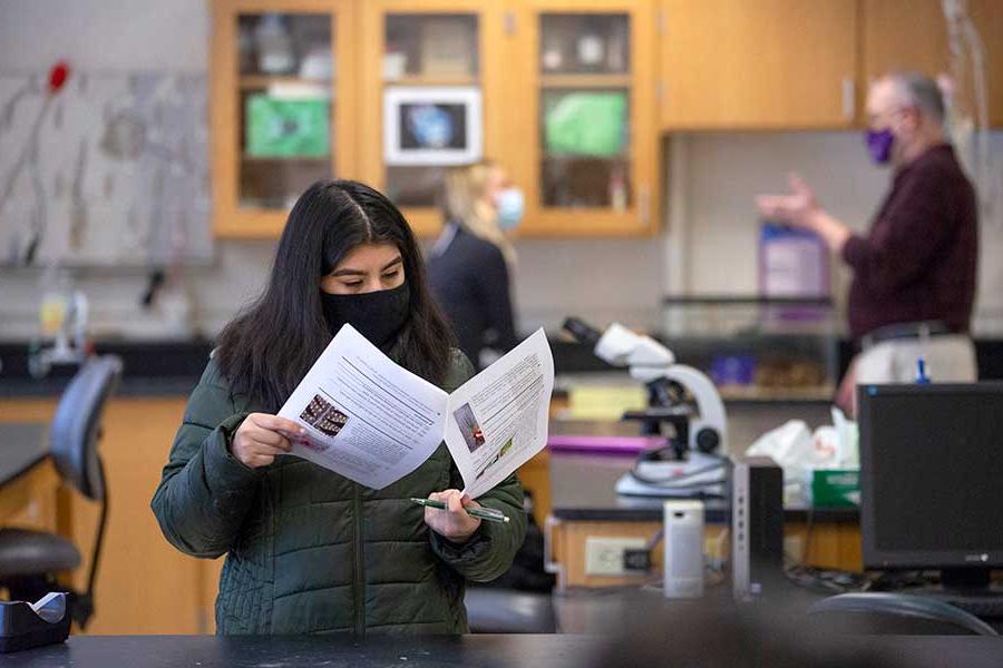 Student standing in a lab reading an in-class exercise.