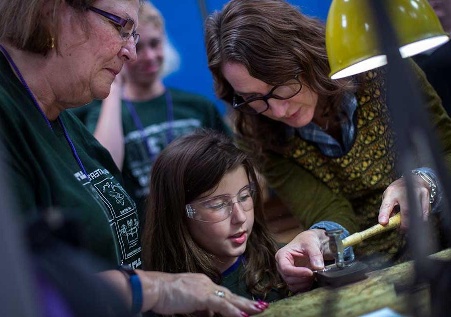 Teresa Faris helps a child and her with a heart-shaped pewter medallion.