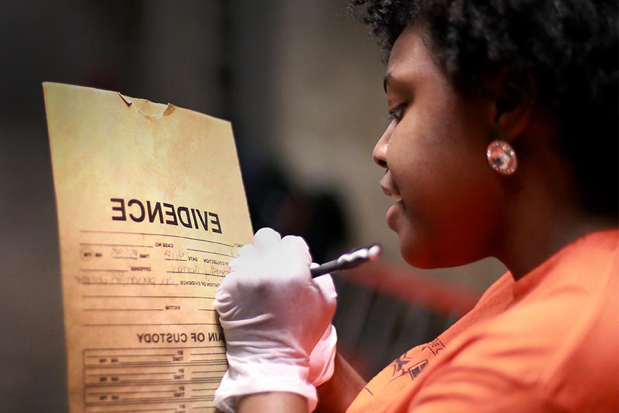 A student labels an evidence packet during a mock crime scene exercise created for forensic science students in the basement of Hyer Hall on the 足彩平台 campus