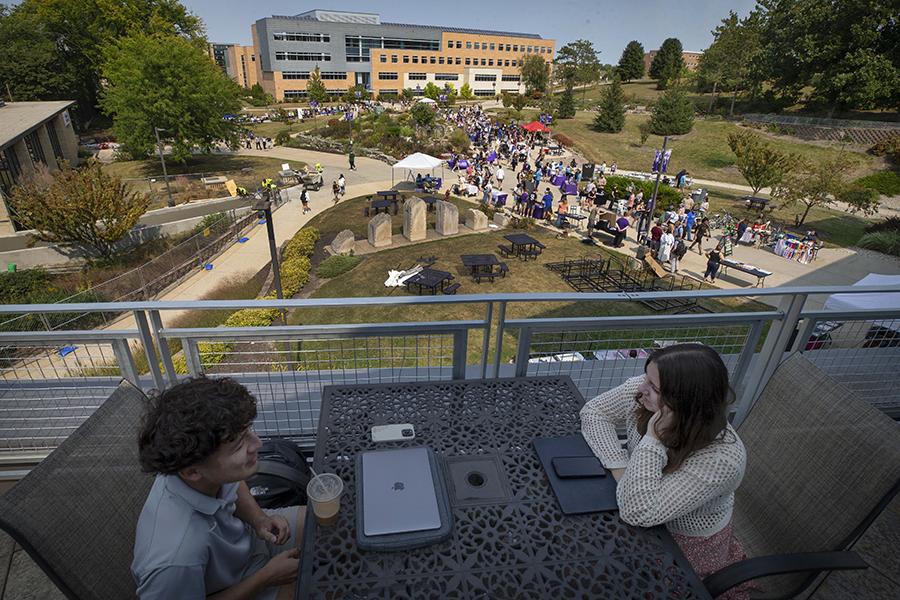 Students fill the sidewalks in the middle of campus with Hyland Hall in the background.