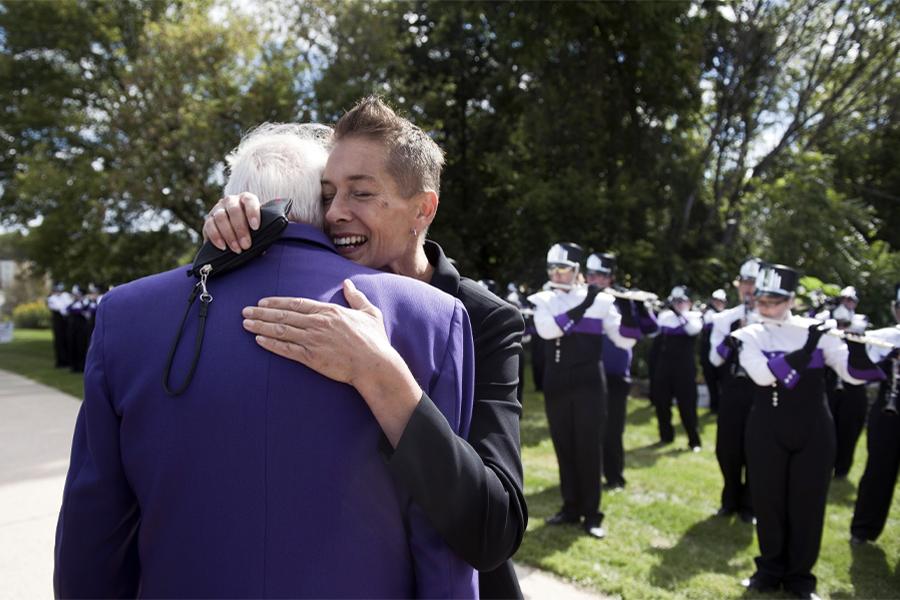 Two people hug while the Marching Band plays behind them.